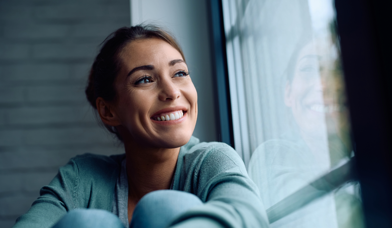 Woman smiling while looking out of a window