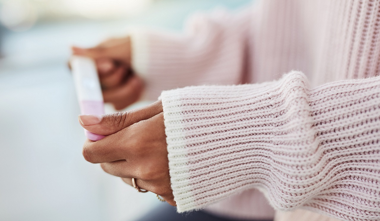 A woman holds a pregnancy test between her hands.