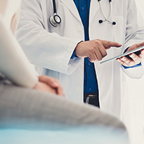 A person in a doctor's office speaking with a physician. 