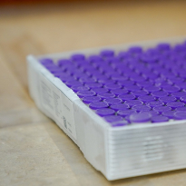 A tray of purple-topped medical vials