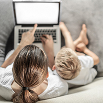 An aerial view of a woman and her young son looking at a computer screen.