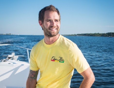 TIRR Memorial Hermann patient, James Durham, smiles while gazing out of the water from the bow of a boat. 