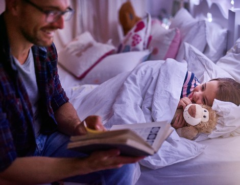 man with child smiling holding teddy bear