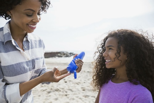 Mother and daughter on beach with sunblock
