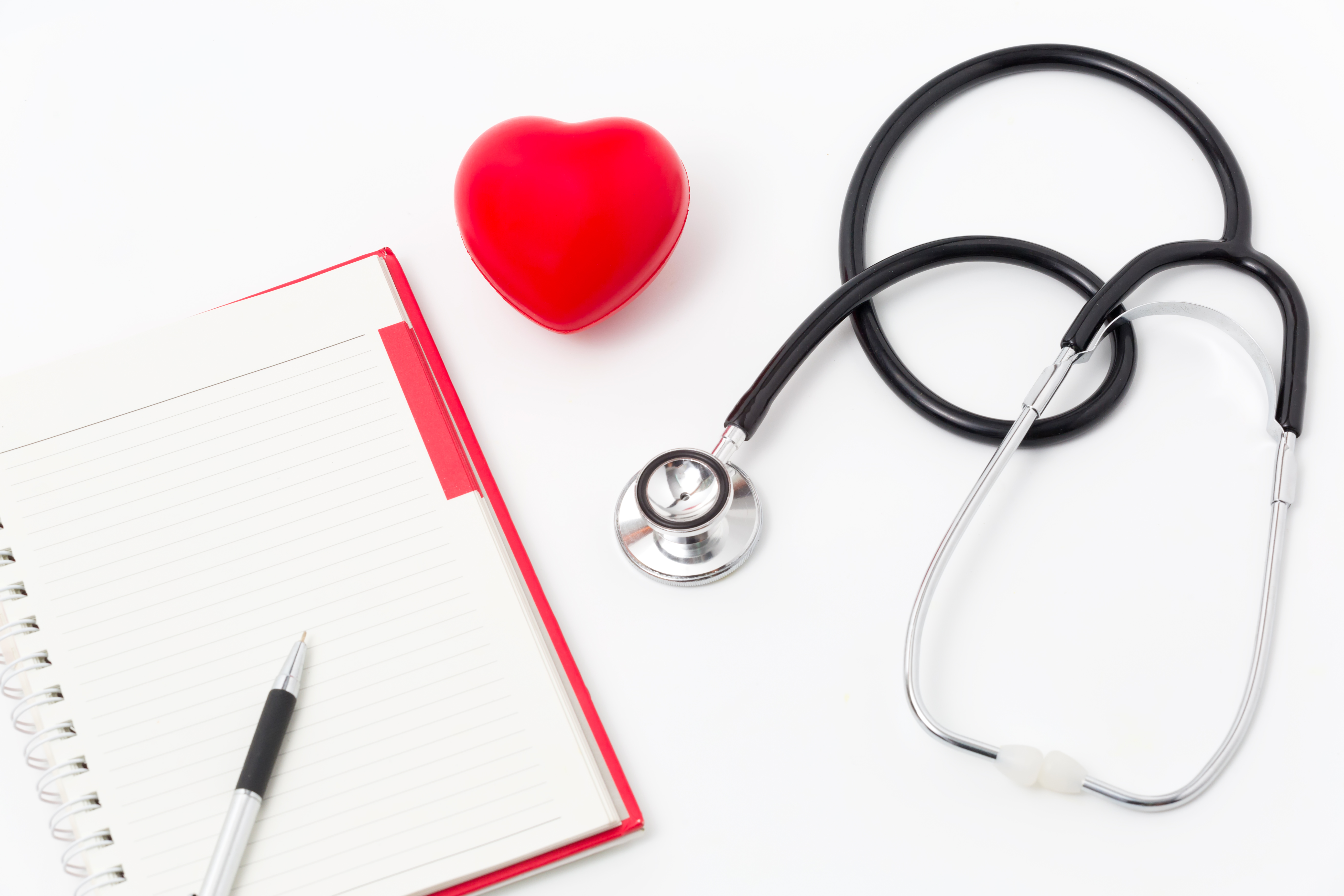 Stethoscope, clipboard and heart stress ball on table