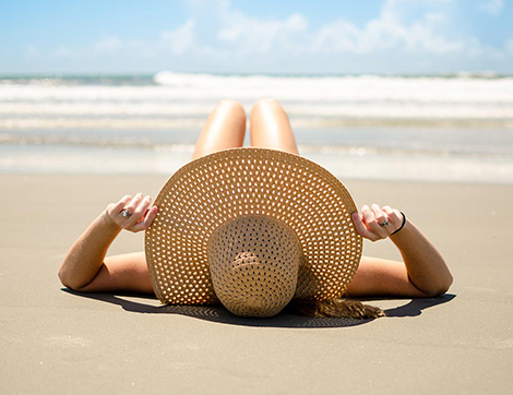Woman in a hat lying on the beach