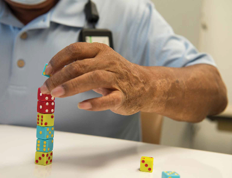 TIRR Memorial Hermann patient, Hector Alvarez, carefully stacks dice as part of physical therapy.