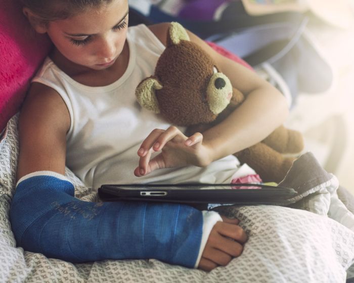 child in cast holding bear
