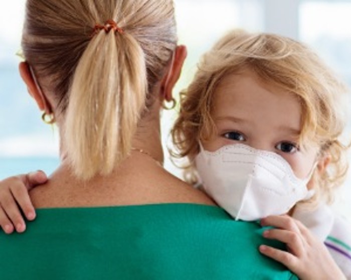 child in mask hugging mom