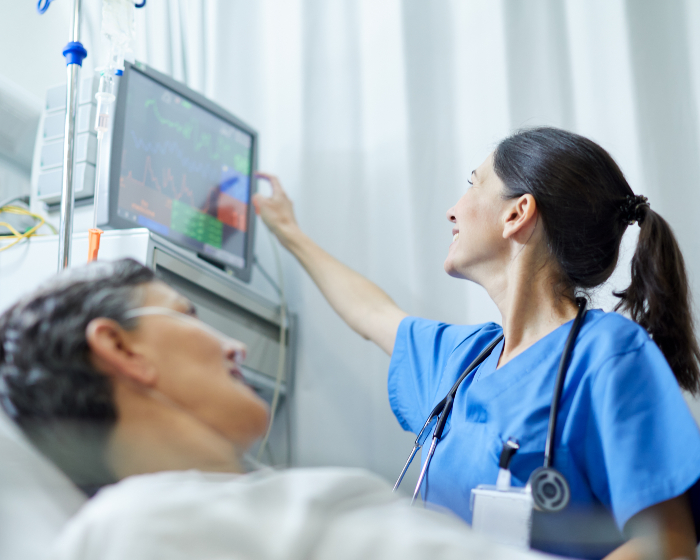 A physician looks at patient's vitals in a hospital setting