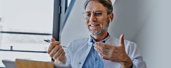 man smiling and holding pen looking at ipad