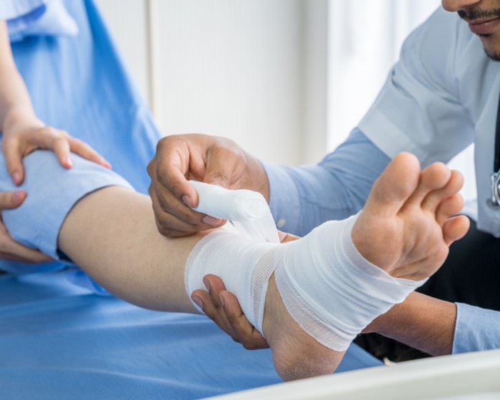 Doctor bandaging wound on foot