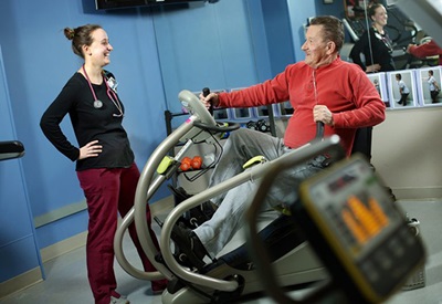 Doctor helping patient on exercise machine